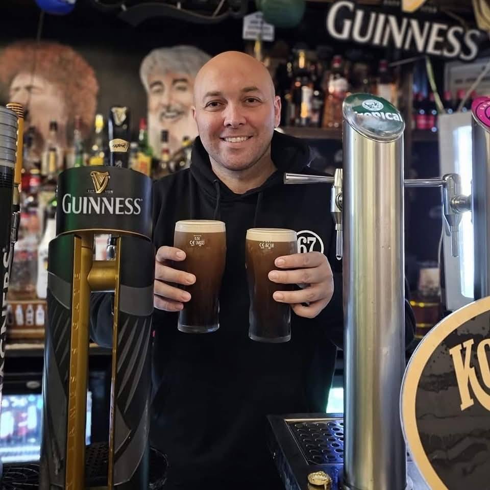 David pouring two pints of Guinness behind the Bar 67 bar